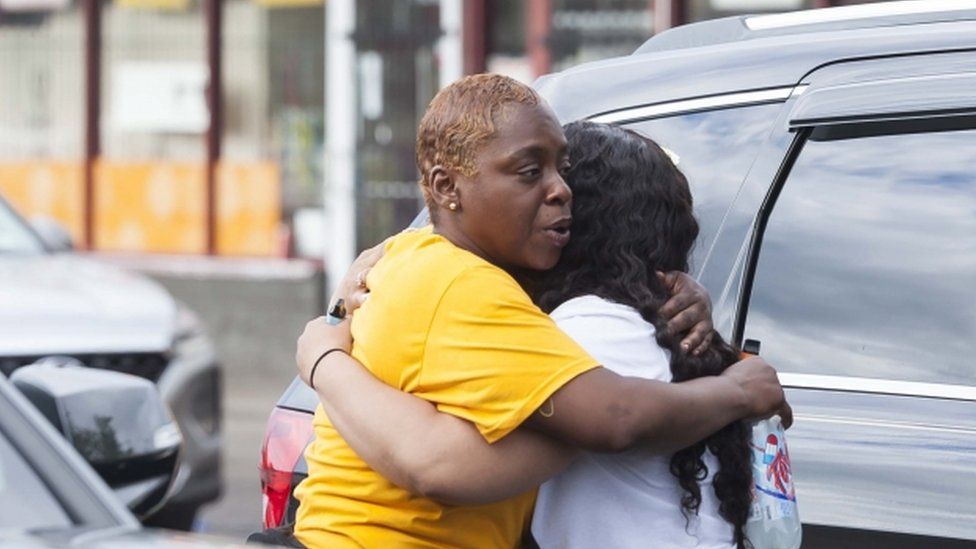 Two people hug near the scene of a shooting at the Tops Friendly Market supermarket in Buffalo, New York on 14 May