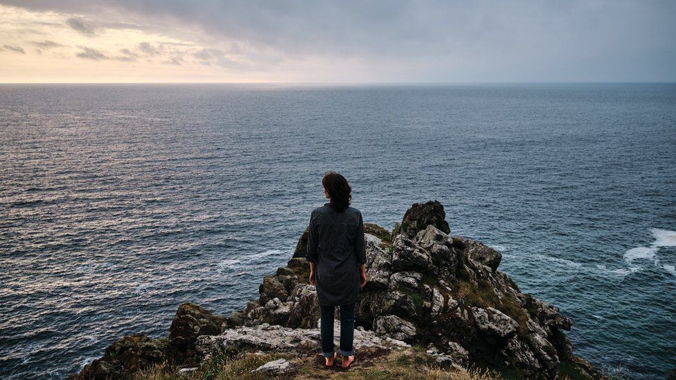 Person standing near a cliff edge. Artwork called Meet me at the Edge by Ian Kingsnorth