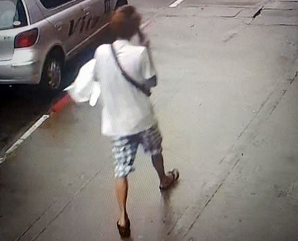 Изображение с камеры видеонаблюдения, опубликованное военными, на котором мужчина проходит мимо машин, разговаривая по телефону