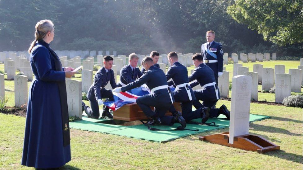 The RAF's Queen's Colour Squadron (QCS) remove the Union Flag from Flt Sgt Hurrell's coffin before laying him to rest