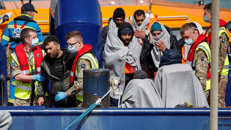 Members of the UK military help migrants come ashore at Dover