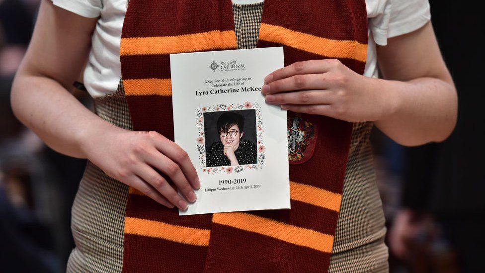A mourner wearing a Harry Potter scarf holds an order of service.