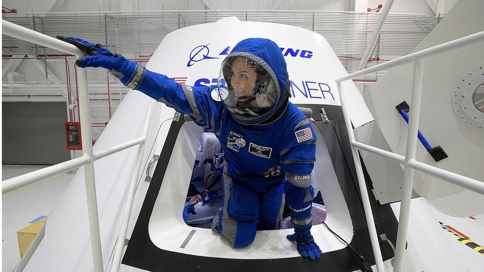 Boeing propulsion engineer Monica Hopkins climbs out of a mockup of the CST-100 Starliner crew module, while wearing a newly-designed spacesuit.