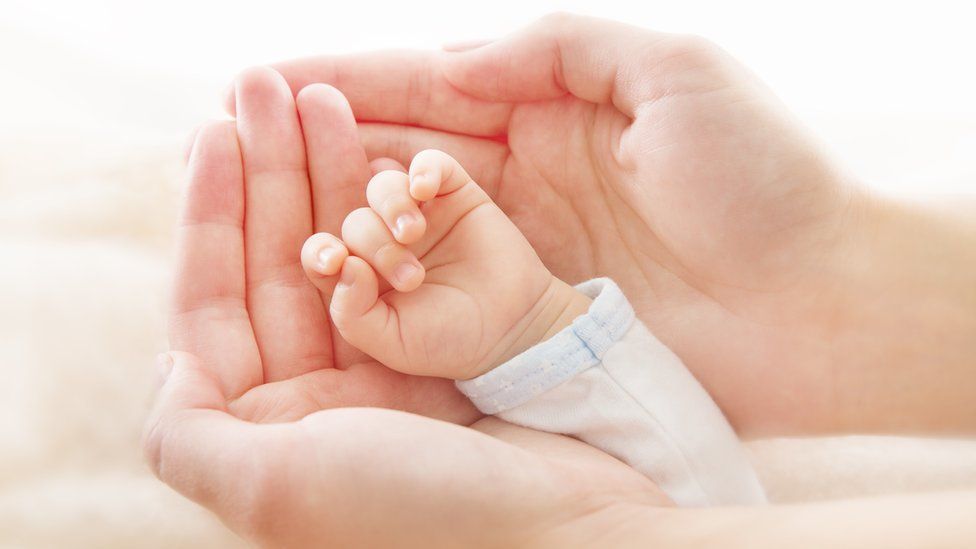 Mum holding new born baby's hand