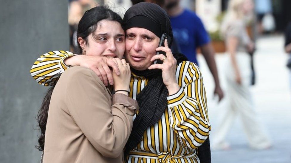 People react in front of the Fields shopping centre during evacuation by armed police