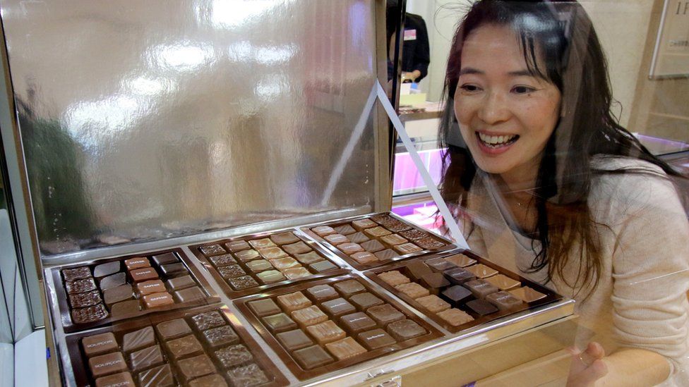 A woman looks at a tray of chocolates