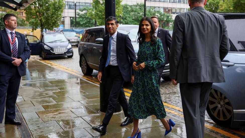 Rishi Sunak and his wife Akshata Murty step out of a car in Manchester on Sunday
