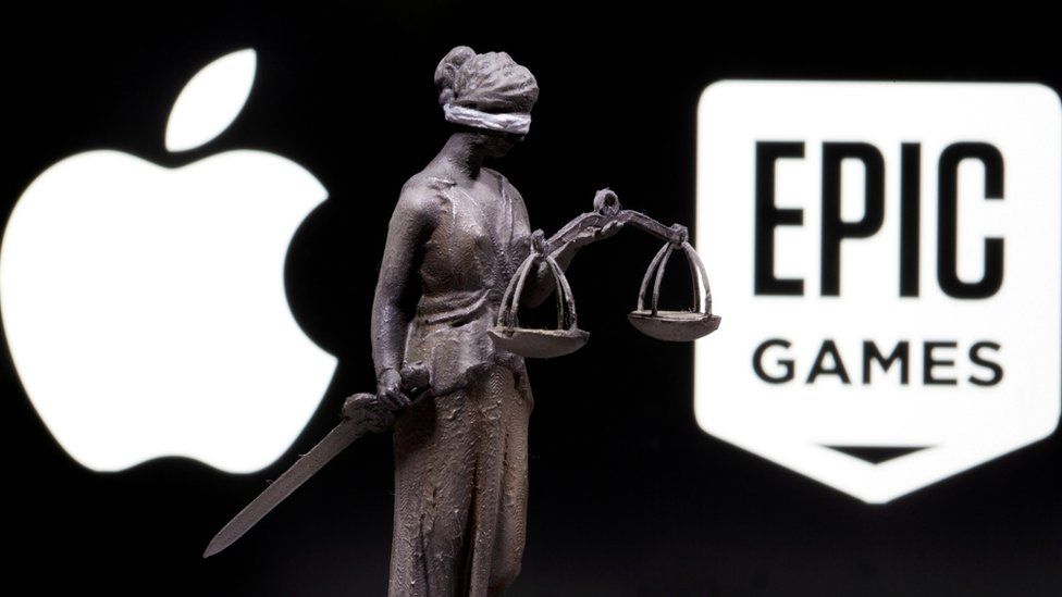 Логотип Apple, логотип Epic и напечатанная на 3D-принтере статуя олицетворения Справедливости с мечом и чешуей между ними