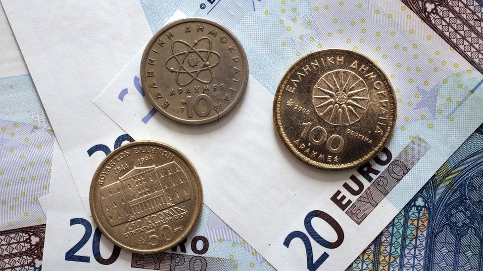Greek Drachma coins sit on 20-Euro money notes