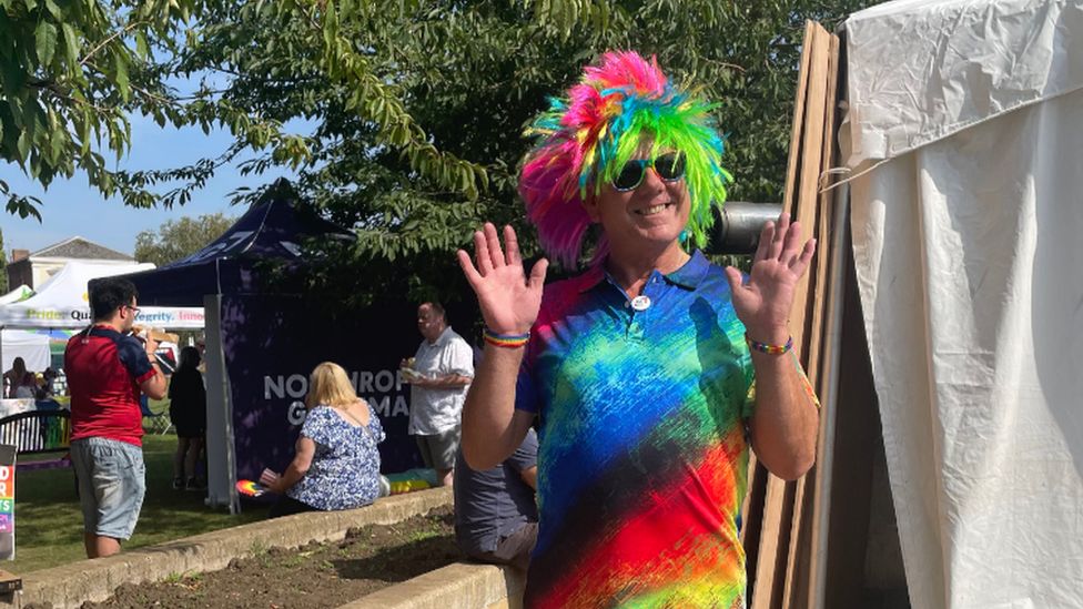 A man wearing a rainbow t-shirt and wig