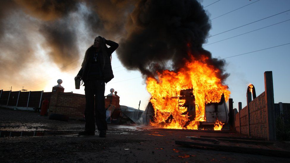 A protestor stands in front of a burning caravan during the 2011 evictions