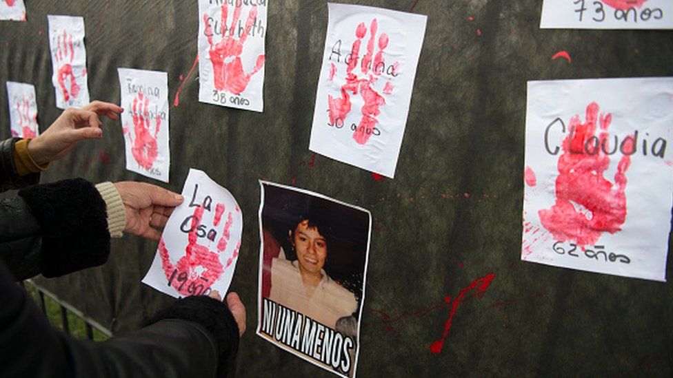 A woman places a paper with her slain sister's nickname next to her picture during 'Ni una menos' (Not One Less) march against femicides in Buenos Aires, on June 3, 2016