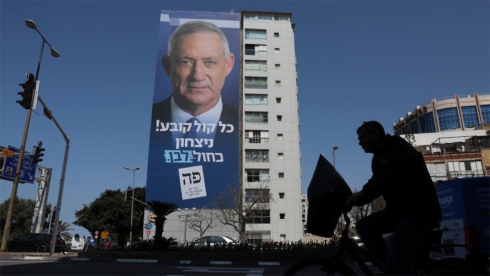 A man passes a Blue and White billboard in Tel Aviv showing Benny Gantz (9 April 2019)