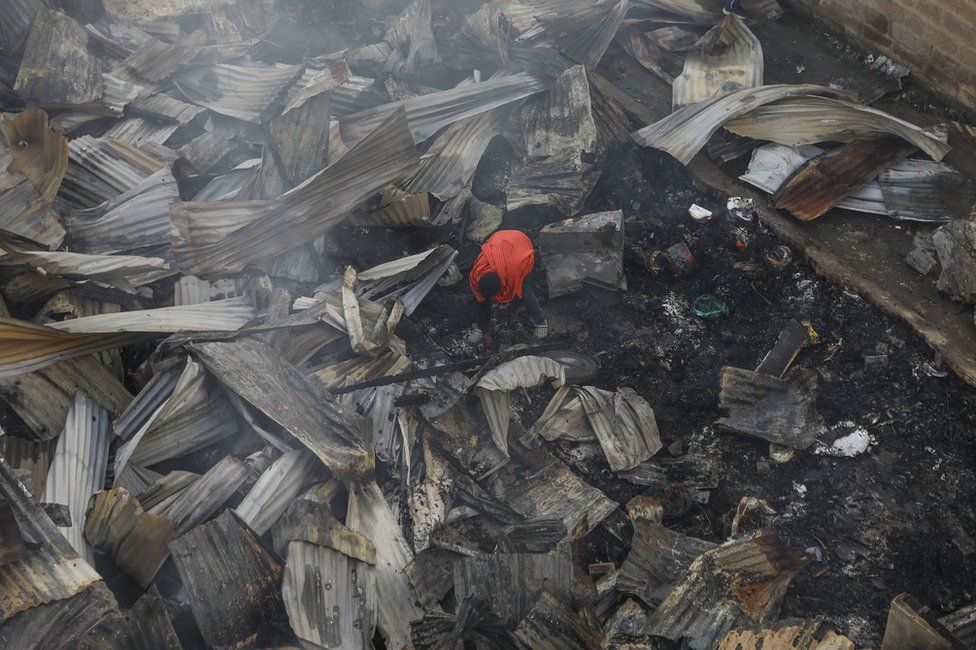A man stands in the wreckage of a burnt house in Embakasi, Nairobi, Kenya.