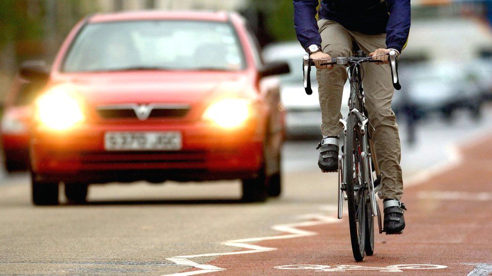 Cyclist using a cycle lane alongside heavy traffic in Cambridge, 2021