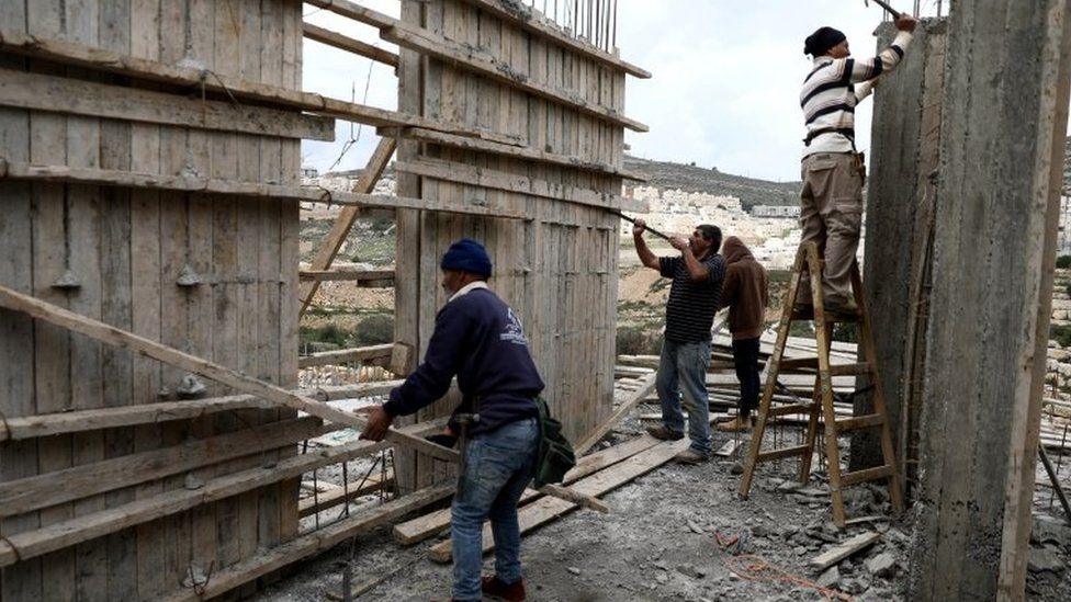 File photo showing Palestinians working at a building site at the Israeli settlement of Ramat Givat Zeev on 19 March 2020