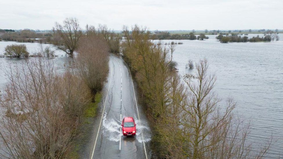 A driver making their way through surface water on the A1101 in Welney, Norfolk, where the rivers Delph and New Bedford have flooded