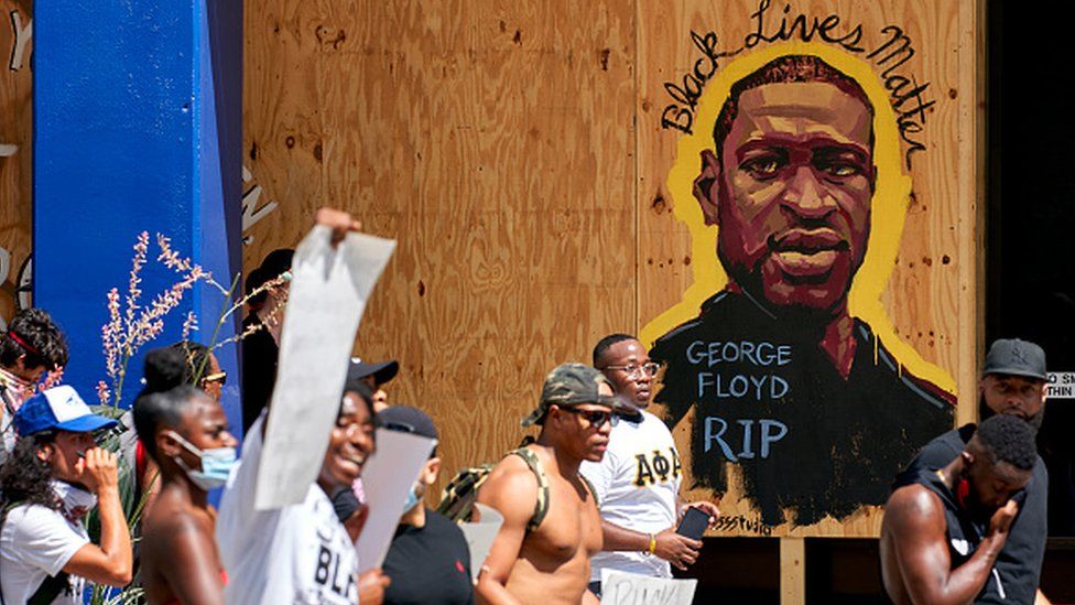 Demonstrators march past a mural remembering George Floyd in Texas