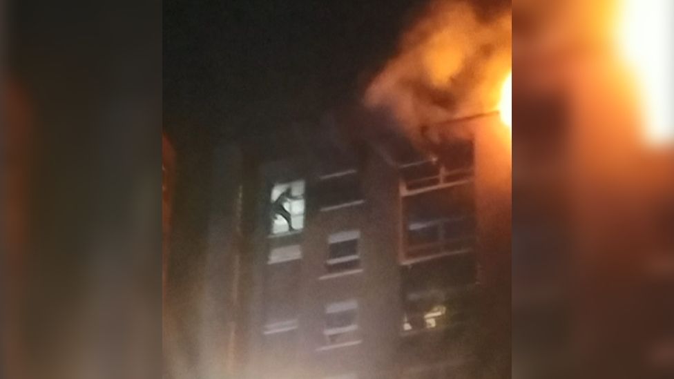 Shadow of man in the window of a burning building