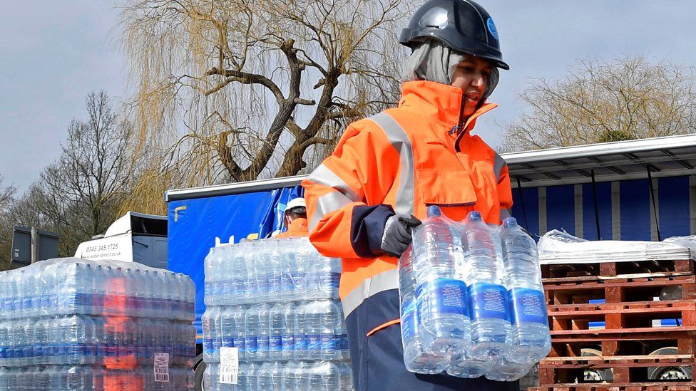 A Thames Water operative collects bottled water for distribution in Hampstead in London, Britain