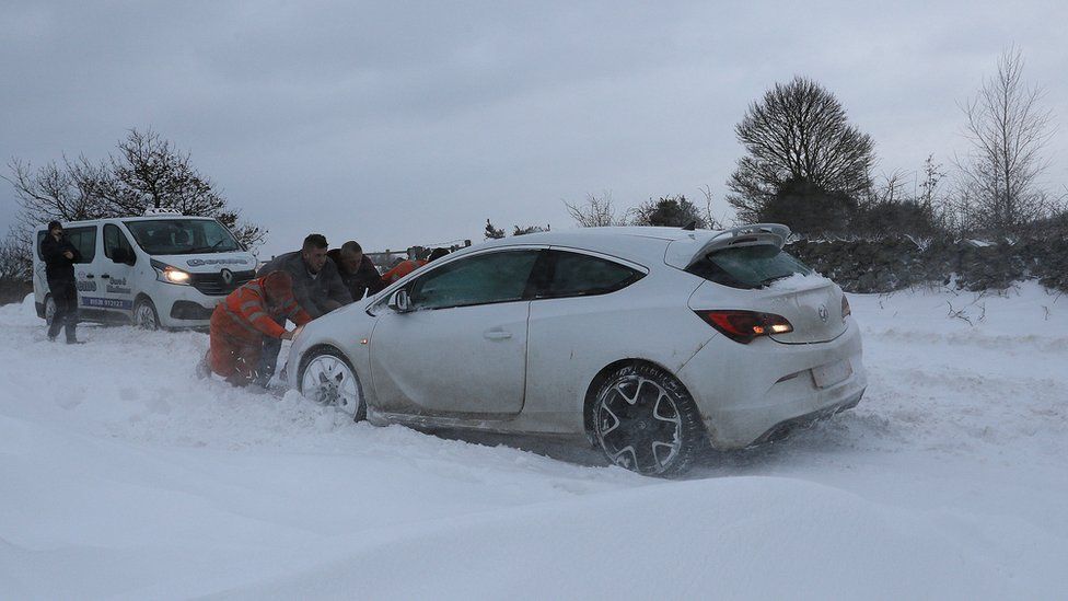 Men push a car in the snow