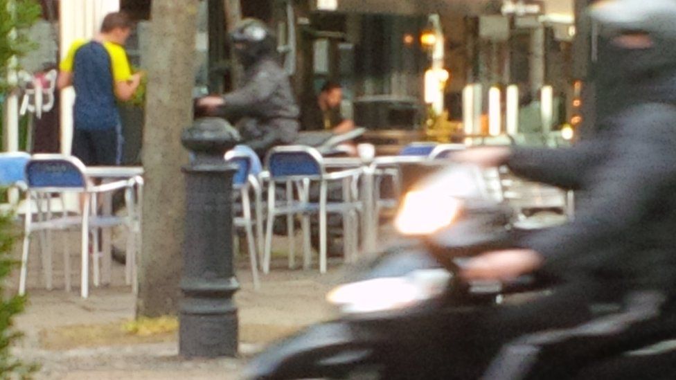 Moped riders drive through restaurant tables