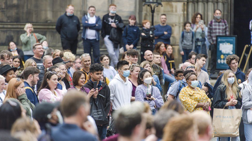 Members of the public wear masks on Edinburgh's Royal mile as street performers entertain crowds during the Edinburgh Fringe Festival 2021 on August 19, 2021 in Edinburgh