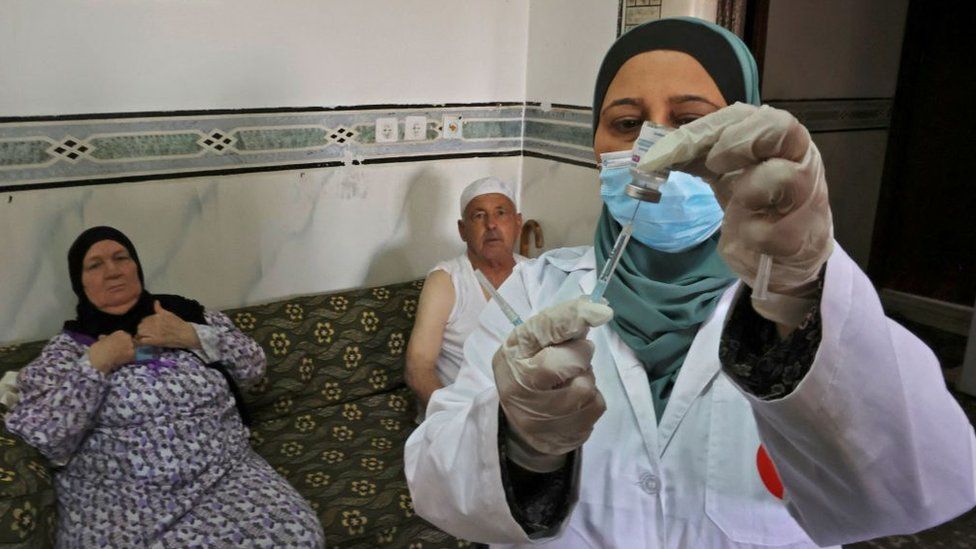 Сотрудник министерства здравоохранения Палестины вакцинирует пожилых палестинцев от коронавируса COVID-19 в деревне Дура недалеко от Хеврона на оккупированном Западном берегу
