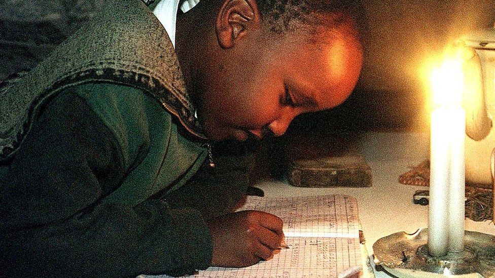 Newton Njenga does his schoolwork using a candle