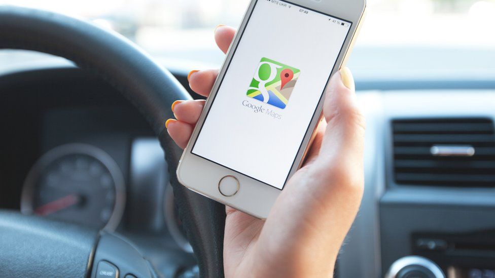 An unidentified woman holds a phone showing a Google Maps icon