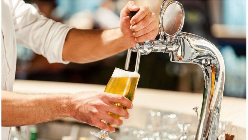 man pouring pint of beer