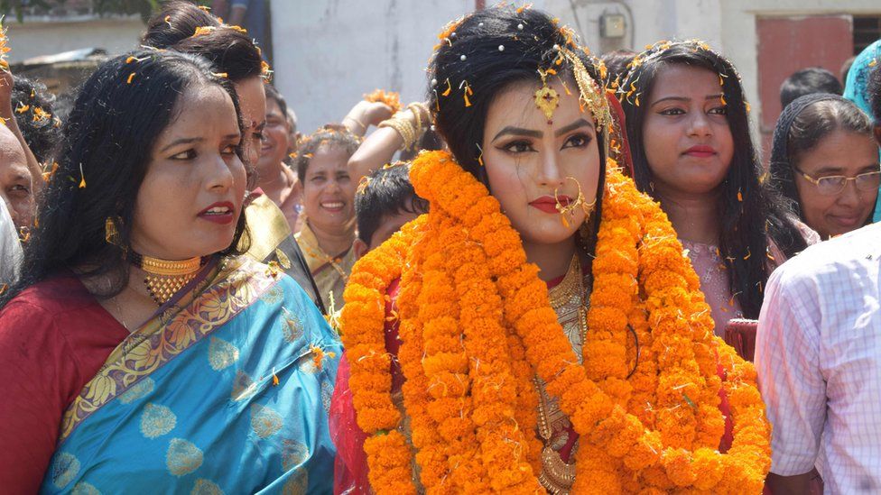 relatives of groom Tariqul Islam welcome bride Khadiza Akter Khushi (C) with a floral wreath as she arrives to groom"s house during their wedding in Meherpur