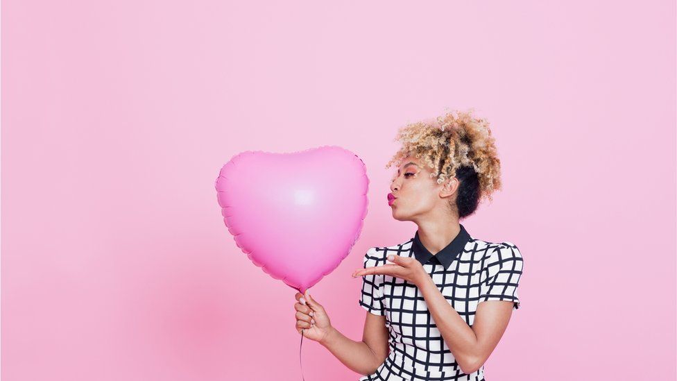 Woman holds pink heart-shaped balloon