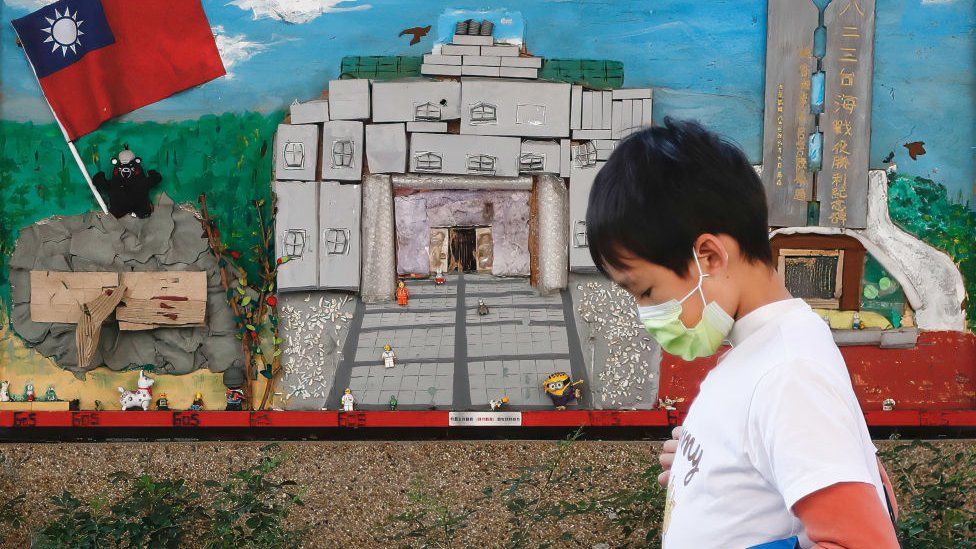 A kid wearing a mask walks past a mural with a national flag of Taiwan amidst a recent cluster of domestic transmissions of Covid-19 ahead of the Lunar New Year.