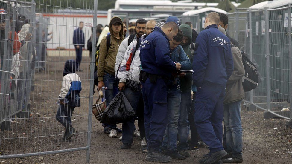 Migrants are checked by police as they arrive at a refugee camp at the Hungarian-Serbian border near Roszke on 11 September 2015