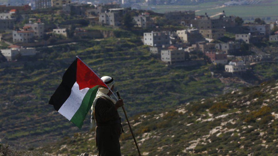 Мужчина держит палестинский флаг во время акции протеста в Бейт-Даджане на оккупированном Израилем Западном берегу 26 февраля 2021 г.