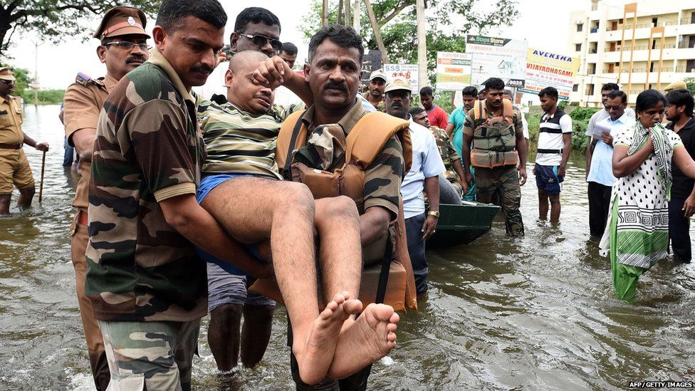 Soldiers carrying a man through flood water