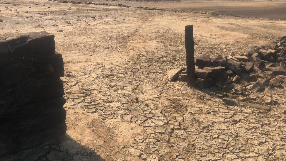 Brown area of dried out land with old bricks on the ground.