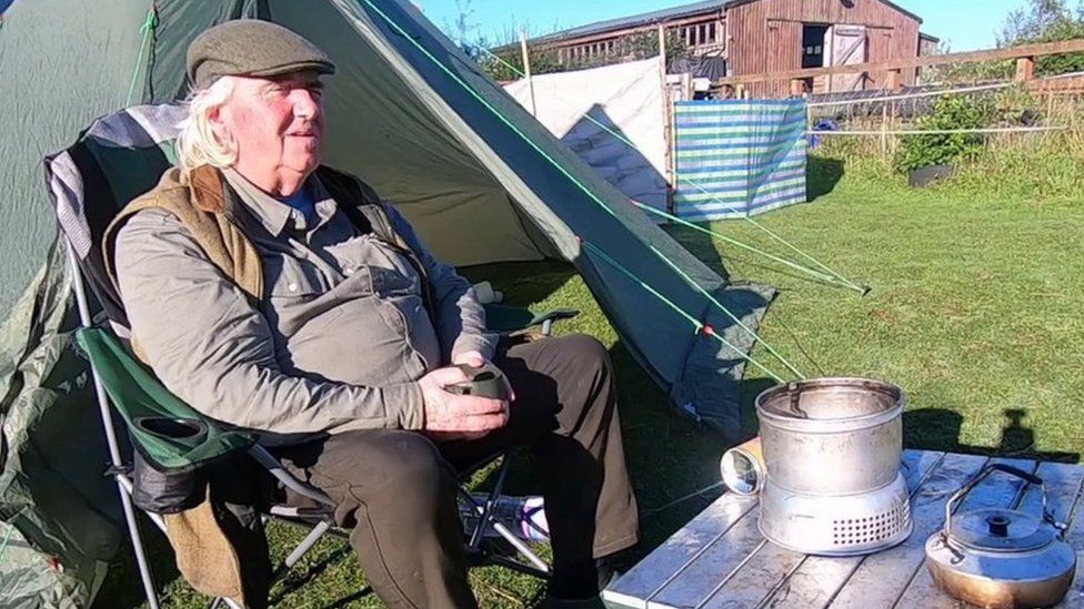 Pat sitting outside his tent having a cup of tea