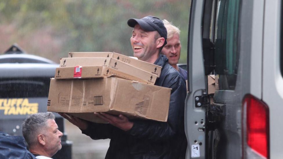 Man holds boxes in rain