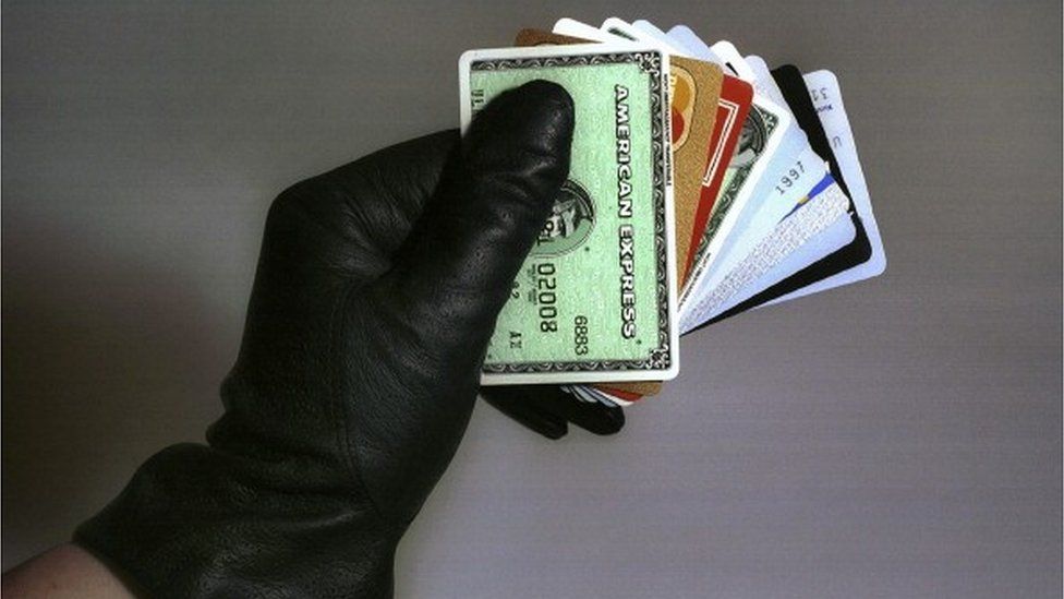 A gloved hand holding bank cards