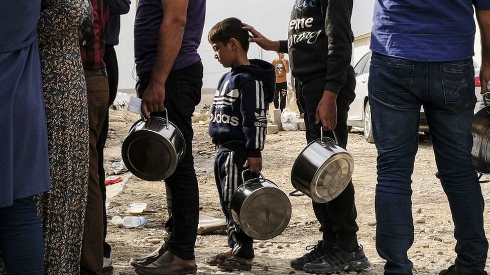 Syrian refugees fleeing the Turkish incursion in Northern Syria wait to receive water, bread and soup at the Bardarash IDP camp on October 17, 2019 in Dohuk, Iraq