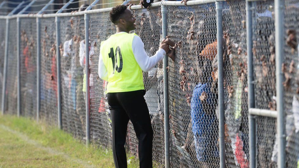 Raheem Sterling greets fans through a metal fence