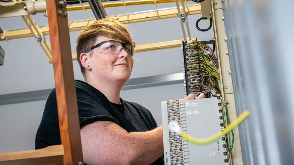 A female Openreach engineer working in a telephone exchange