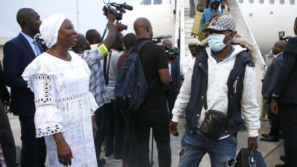 Ivorian Minister of State and Minister of Foreign Affairs Kandia Camara (L) welcomes some of the hundreds of sub-Saharan Africans arriving from Tunisia at the airport in Abidjan, Côte d'Ivoire, on 04 March