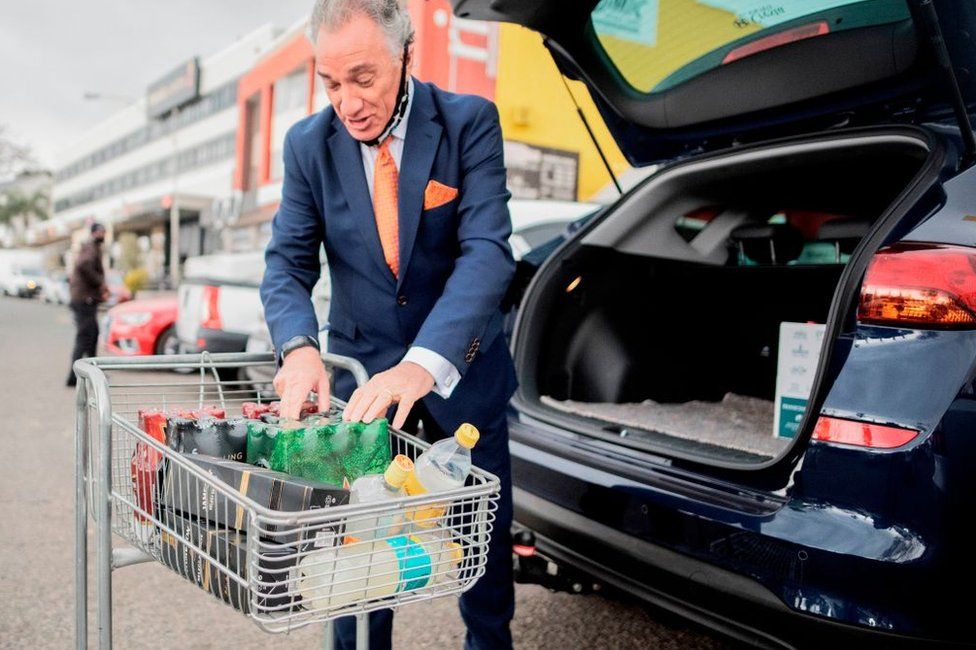 A customer loads alcohol into his car that he bought at a liquor shop in Melville, Johannesburg, on August 18, 2020. - South Africa moved into level two of a five-tier lockdown on August 18, 2020, to continue efforts to curb the spread of the COVID-19 coronavirus. Under level two liquor and tobacco sales will resume.