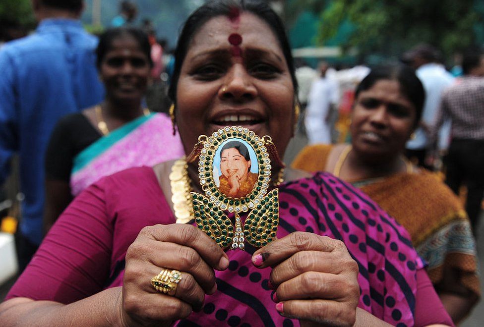 A member of the All India Anna Dravida Munnetra Kazhagam(AIADMK) party displays a pendant with the image of AIADMK leader Jayalalithaa Jayaram as they celebrate in front of her residence in Chennai on May 19, 2016.