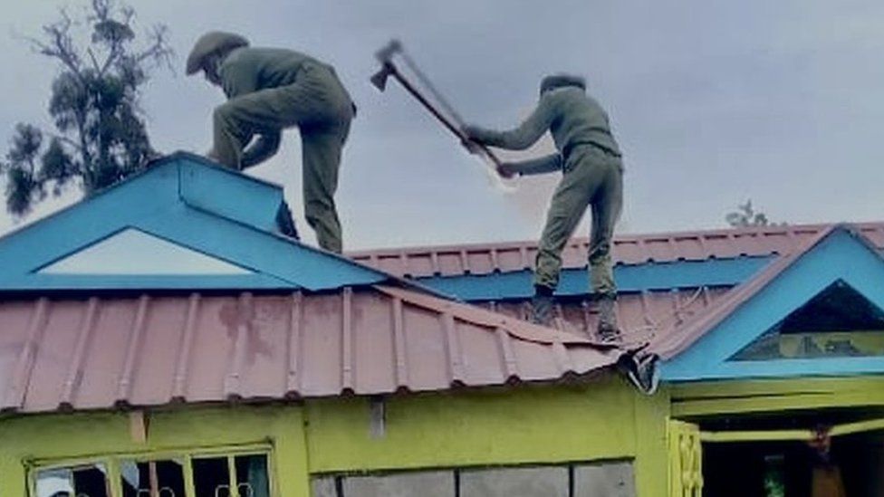 Kenya Forest Service rangers on roof of house with axes