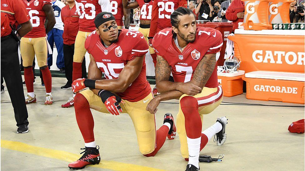 Colin Kaepernick and Eric Reid kneel before a football game, in protest of police violence against black people
