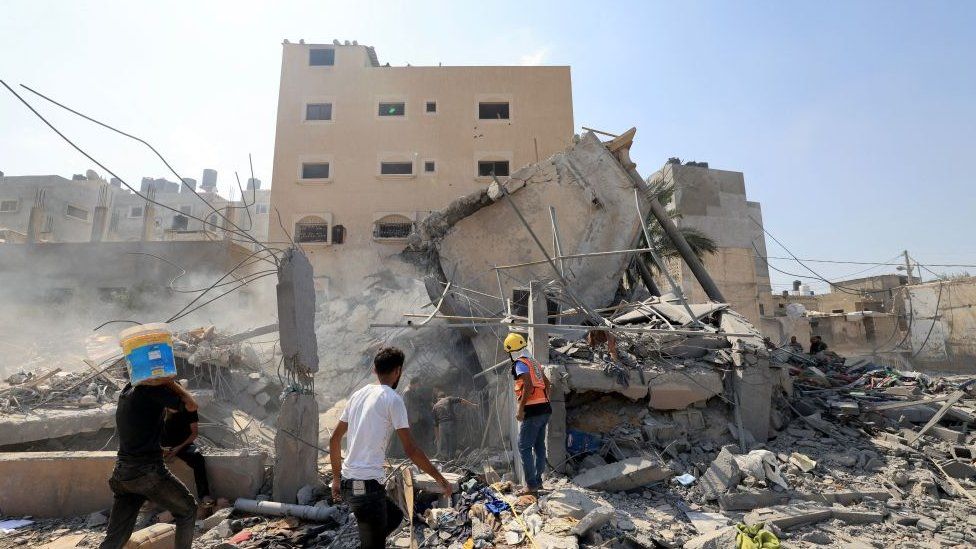 Palestinians survey a building hit by an Israeli strike in Khan Younis